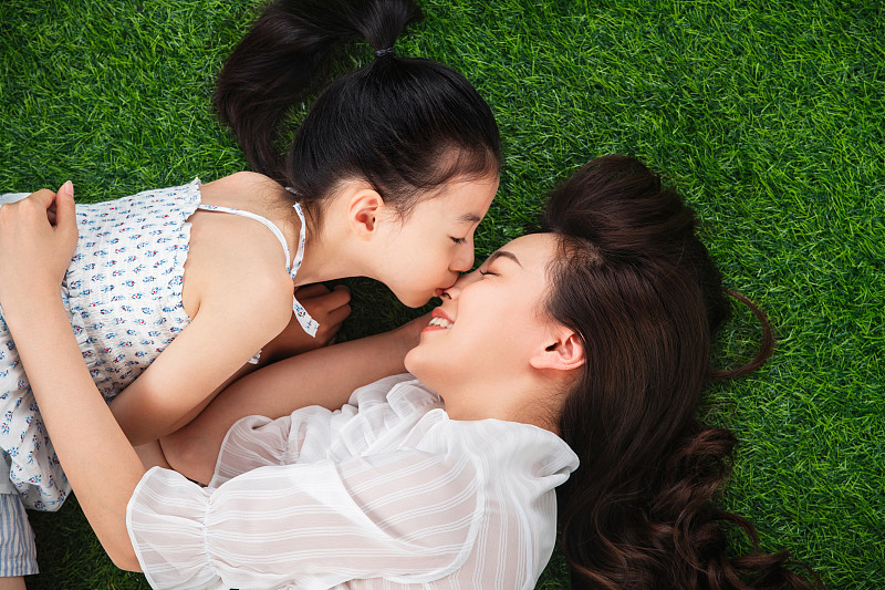 草地上小女孩亲吻母亲图片下载