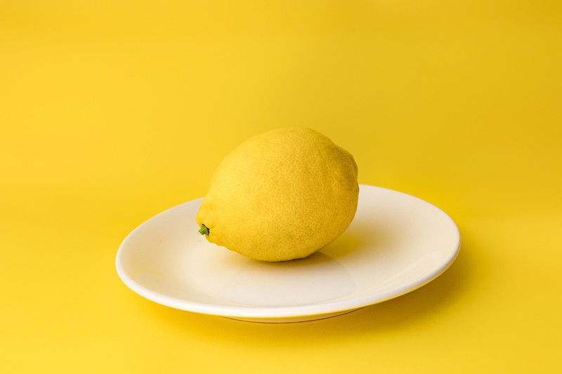 阿塞拜疆巴库，黄色背景下的盘子里的柠檬特写图片下载