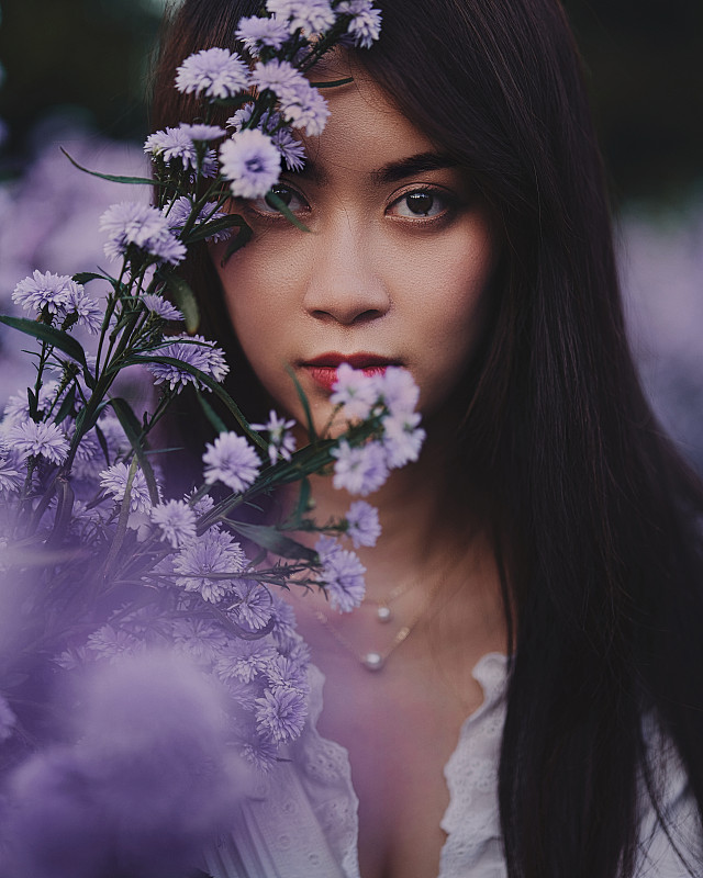 一个年轻的亚洲女人的肖像在紫色开花植物中，泰国清迈图片素材