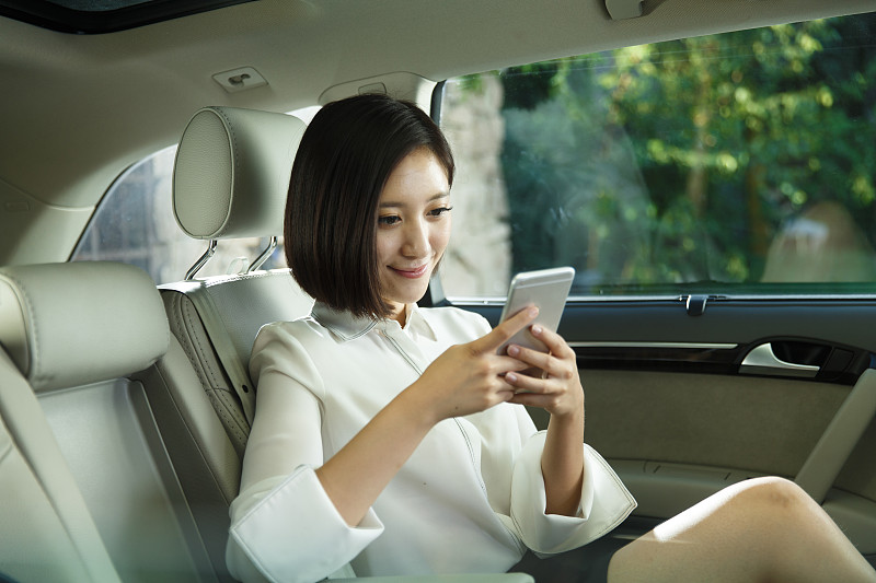 青年女人坐在汽车里看手机图片下载