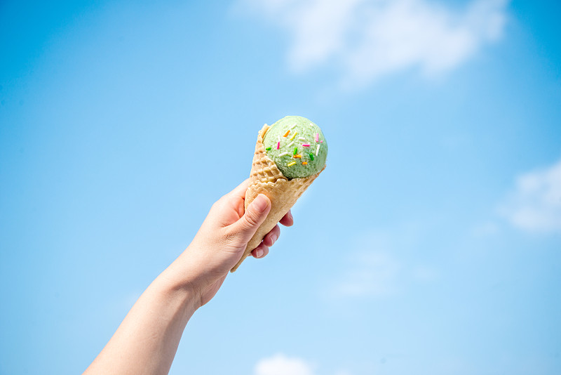 夏季蓝天下女孩手中的甜筒冰激淋图片下载