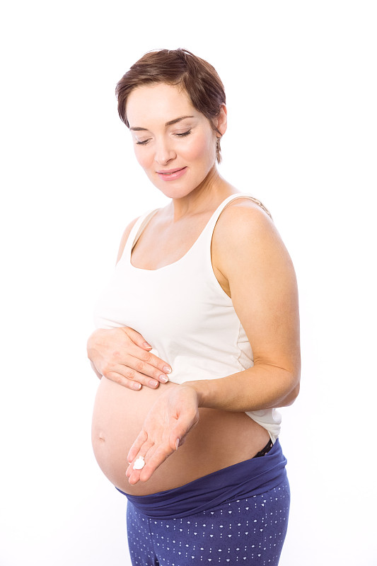 一名孕妇在白色背景上展示身体乳霜图片下载