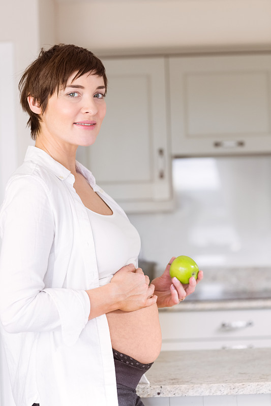 一个孕妇在厨房里拿着苹果图片下载