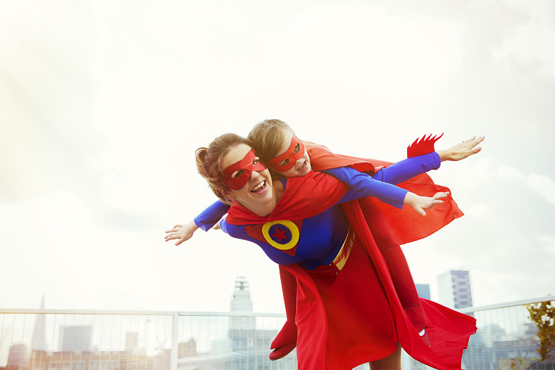 超级英雄妈妈和女儿在城市屋顶上玩耍图片素材