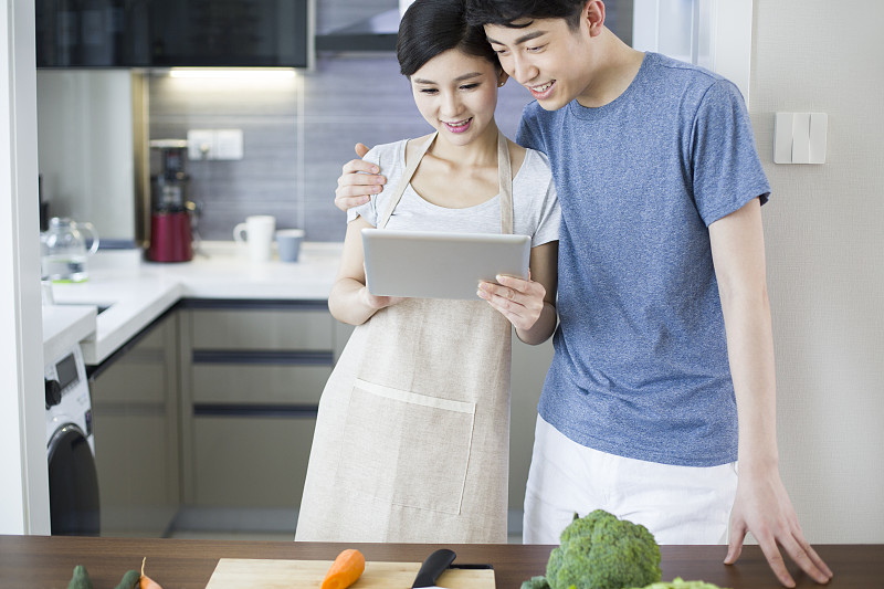 年轻夫妇在厨房使用平板电脑图片素材