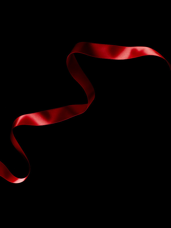 黑色背景上流动的红丝带。图片下载