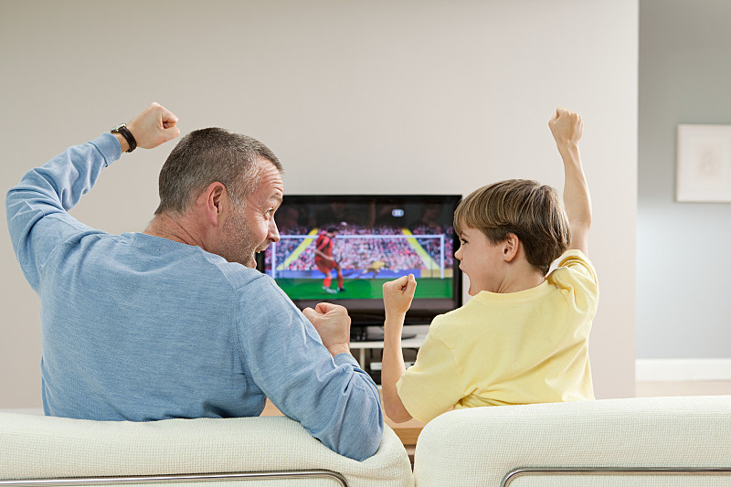 父子俩在电视上看足球比赛图片下载