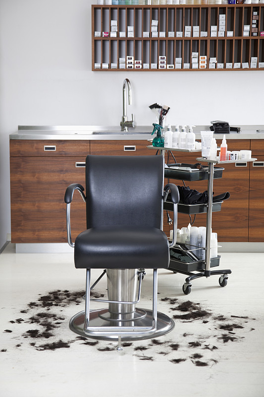 一张空荡荡的理发椅，周围是剪过的头发图片素材