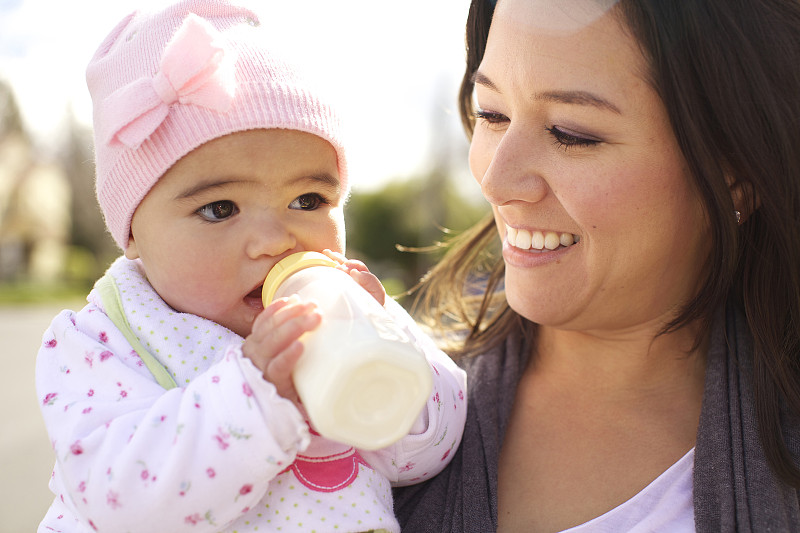 混血母亲看着女婴喝奶瓶图片素材