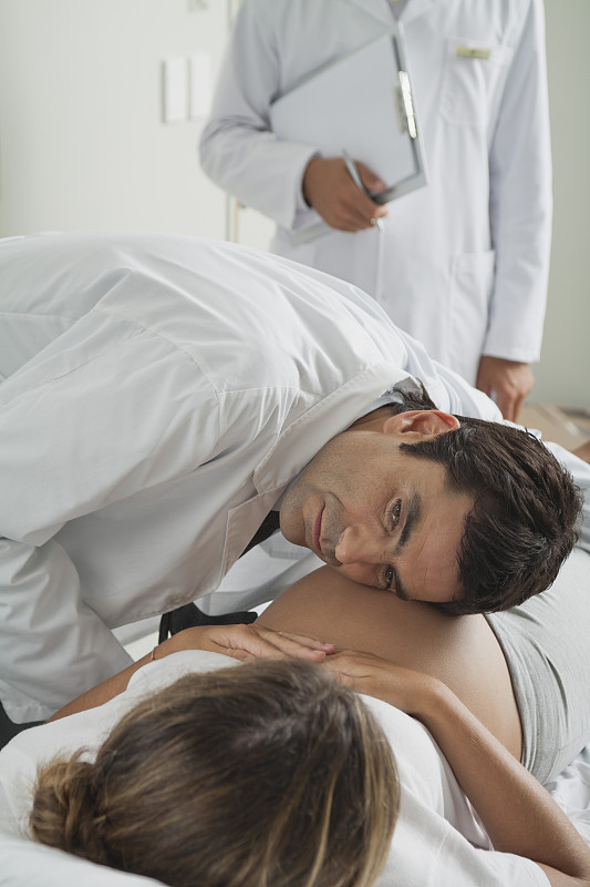 医生用耳朵贴着孕妇的腹部图片下载