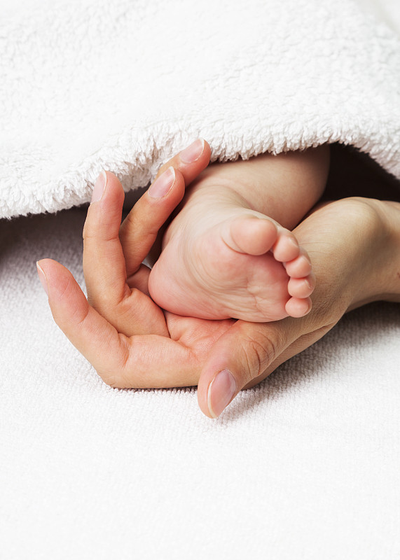 婴儿的脚在妈妈的手里。美丽,柔软和小。图片下载