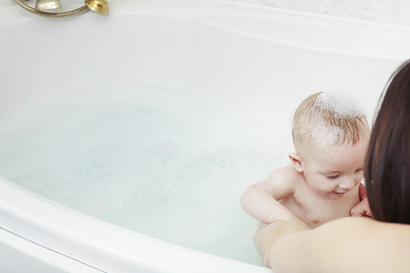 母亲在泡泡浴中给女婴洗澡图片下载