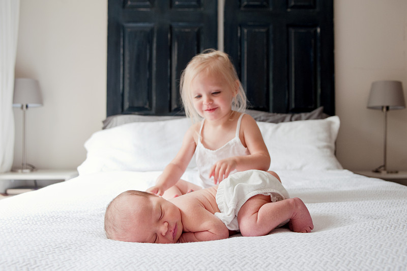 小女孩和刚出生的婴儿在床上图片下载