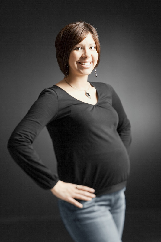 一名孕妇双手叉腰在摄影棚里摆姿势图片下载