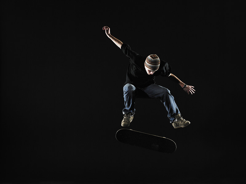 在滑板上表演跳跃的年轻人图片下载