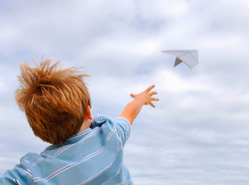男孩(4-6)扔纸飞机，户外，后视镜图片下载