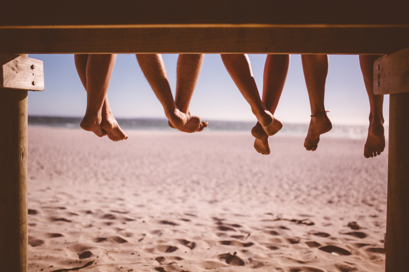 朋友们的腿一起坐在海边的木板路上图片素材