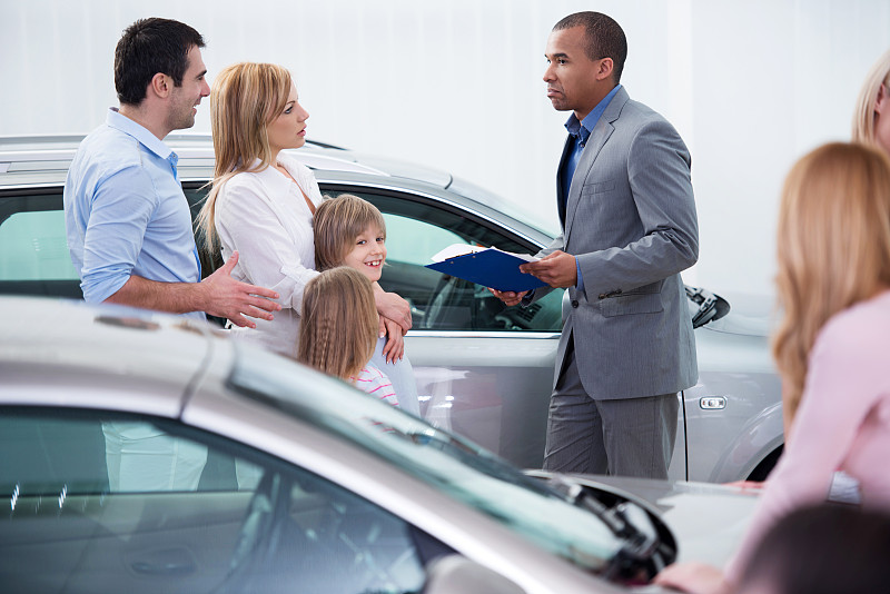 家庭与非裔美国汽车销售人员在展厅交流。图片下载