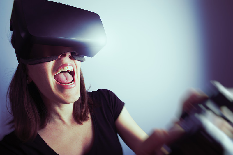 女人用虚拟现实耳机玩电子游戏图片下载