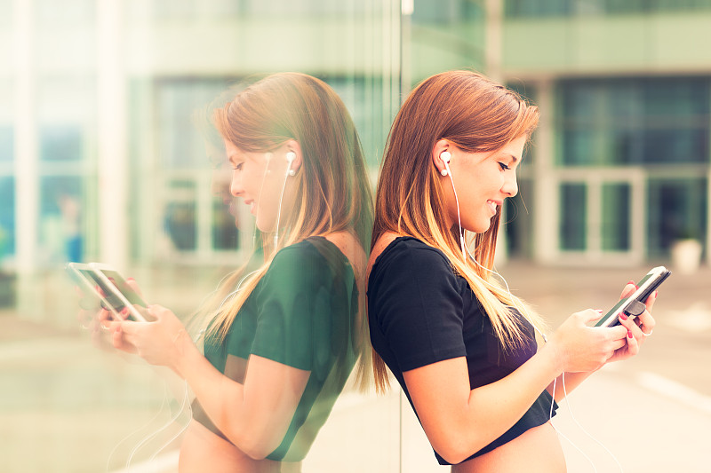 年轻女子在户外用智能手机听音乐图片下载
