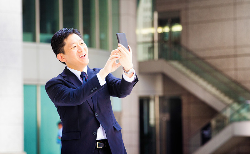 快乐的日本游客用手机自拍微笑图片下载
