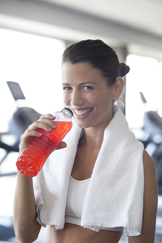 在健身俱乐部用运动饮料补水的女人图片下载