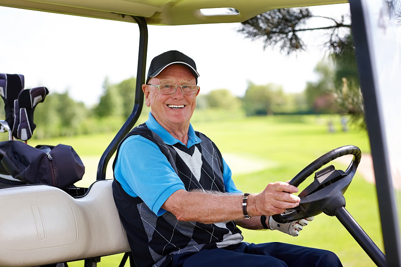 一个成年人坐在高尔夫球车里的肖像图片下载
