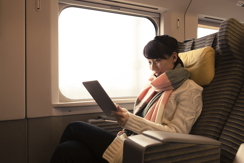 一名年轻女子在火车上使用平板电脑图片下载