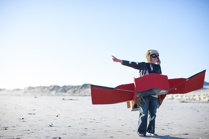 男孩站在玩具飞机和指向海滩图片下载