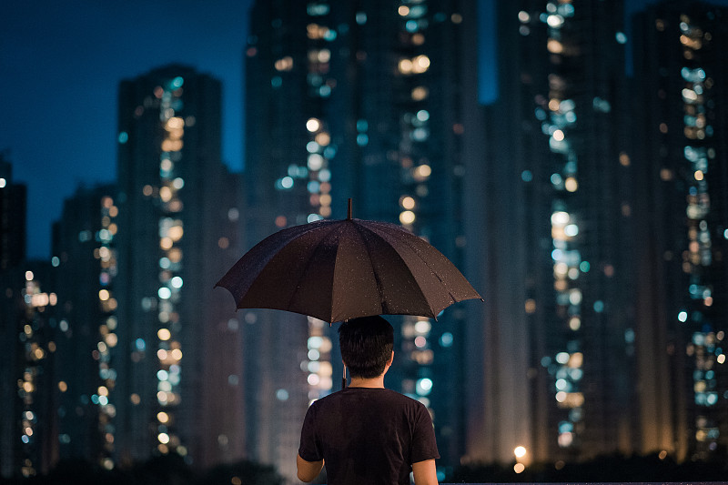 年轻男子在雨天俯瞰城市景观图片下载