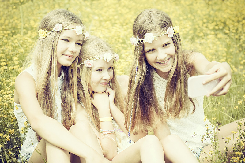 三个女孩戴着花圈在草地上自拍的照片摄影图片下载