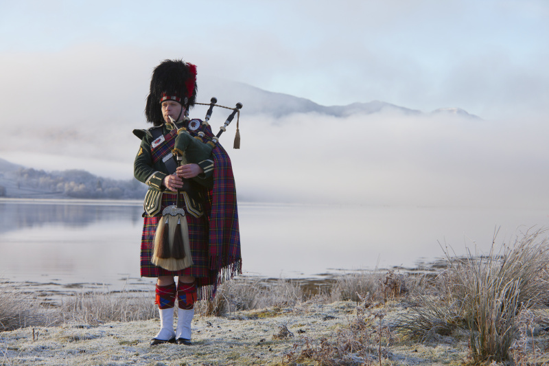 风笛手吹着风笛，站在苏格兰湖边。苏格兰西海岸图片下载