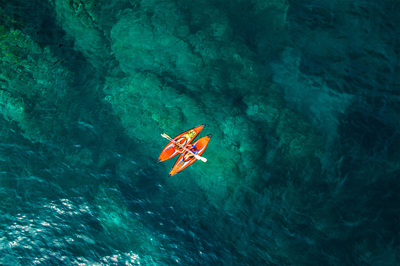 航拍的两个女孩练习皮划艇在一个天堂的地方，在美丽和透明的蓝色海水的夏天的布拉瓦海滩。图片下载
