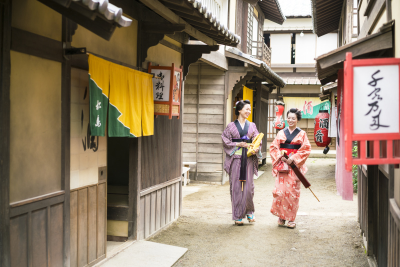 两名妇女撑着雨伞走在日本的一条老街上图片下载