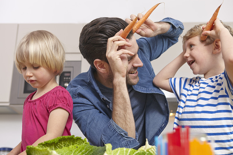 爸爸和孩子们在厨房里玩，做胡萝卜角图片下载