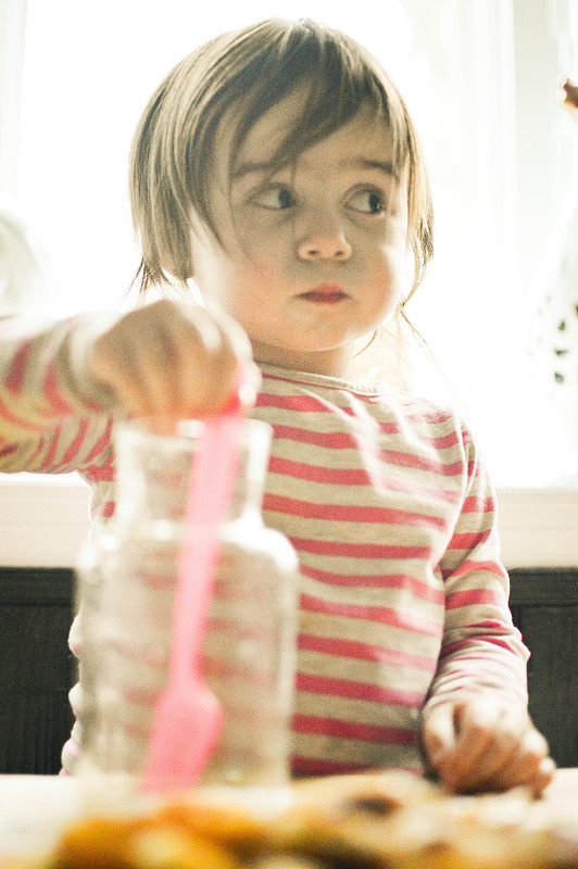 小女孩在玻璃罐里搅拌东西。图片下载