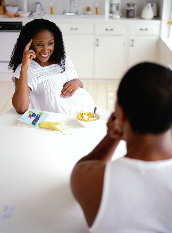 一个孕妇坐在桌子上和她的丈夫说话的高角度视图图片下载