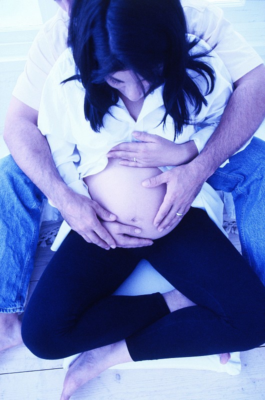 一个男人从后面抱着他怀孕妻子的肚子的高角度视图图片下载