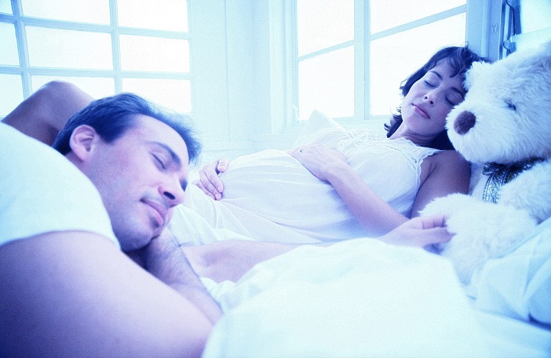 侧面特写一个男人睡在他怀孕的妻子旁边图片下载