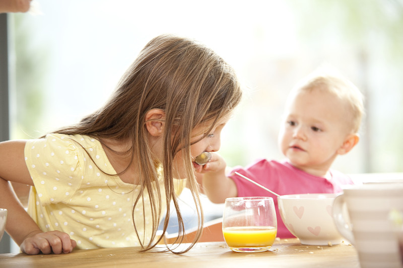 女婴在早餐桌上喂妹妹图片下载