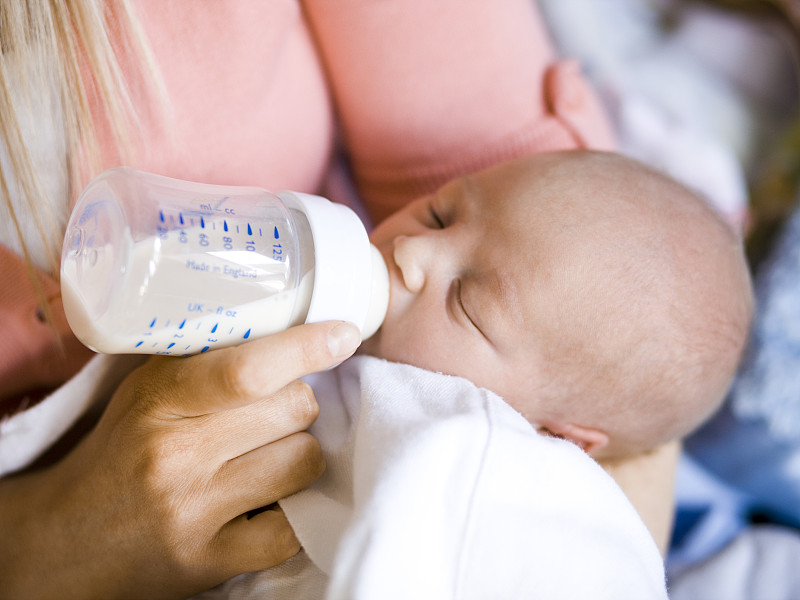 一位妇女用奶瓶喂她的婴儿图片下载