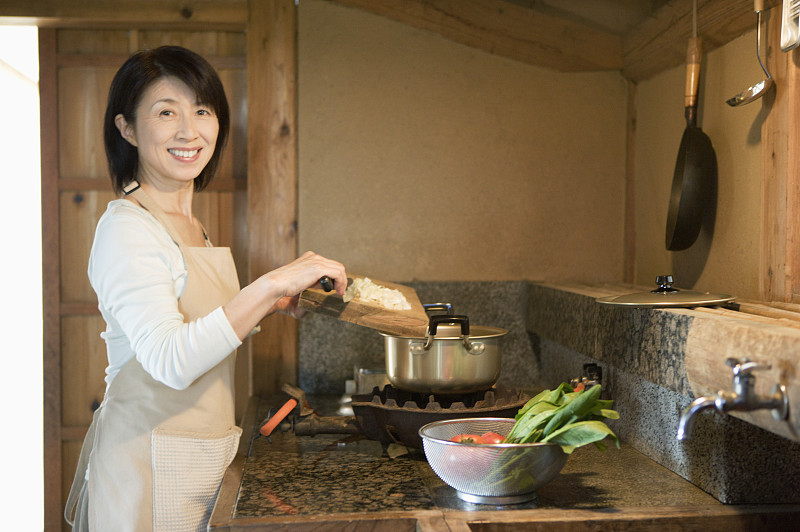 成熟的女人在传统的日本厨房做饭，肖像图片下载