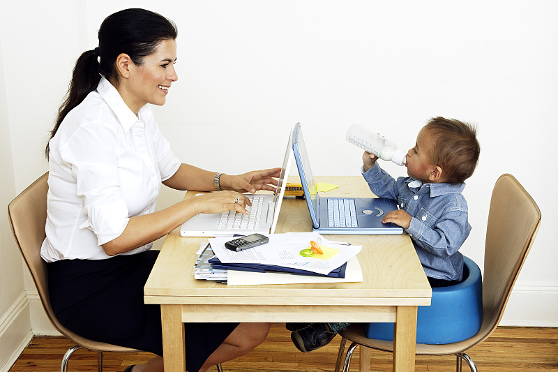 在家工作的女人带着小儿子坐在餐桌旁图片下载