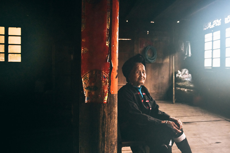 黑暗的房间里，一个中国老妇人坐在凳子上图片素材