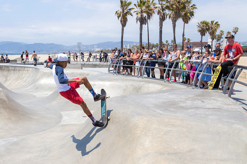 滑板男孩在加州洛杉矶威尼斯海滩的滑板公园练习。威尼斯海滩是洛杉矶最受欢迎的海滩之一图片下载