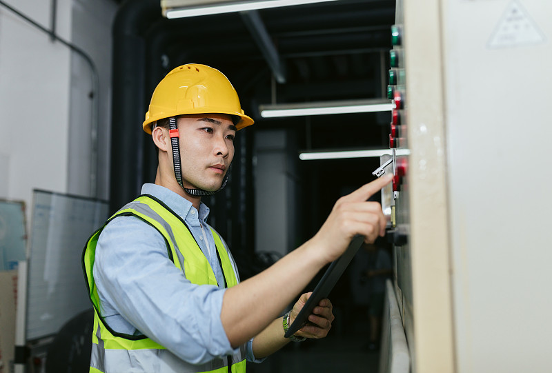 亚洲男性维修工程师在能源控制室工作。工程和商业概念。图片素材