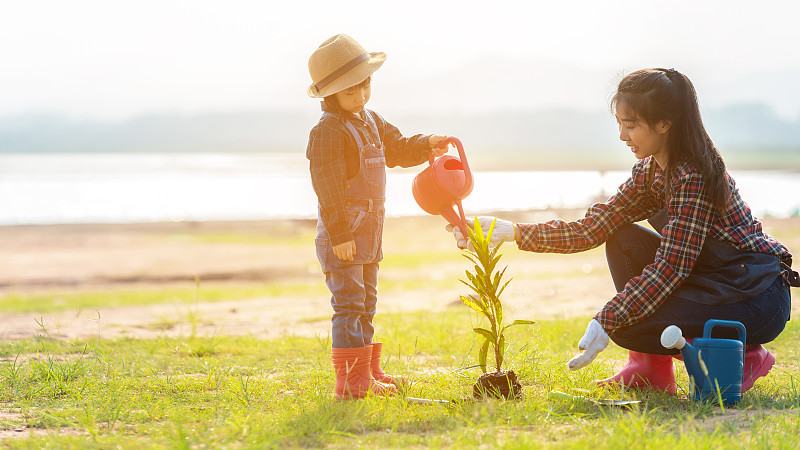 亚洲家庭妈妈和孩子在大自然的春天在户外种植树苗，以减少全球变暖的生长特征，爱护自然地球。人族河流背景图片下载