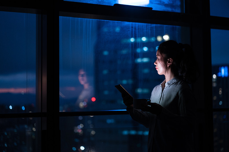 亚洲女性在家里窗户边使用智能手机图片素材