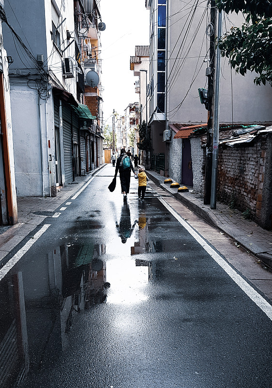 人们走在潮湿的街道在城市的建筑物图片素材