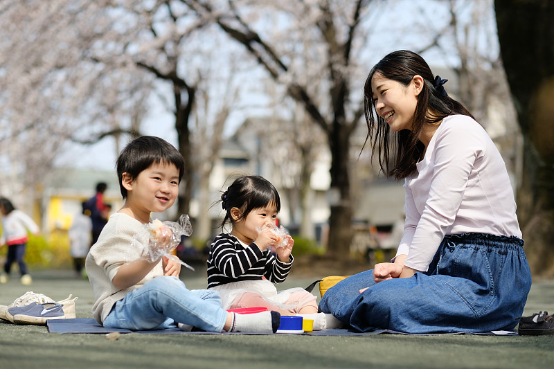 母亲和两个孩子在樱桃树下吃午饭图片下载